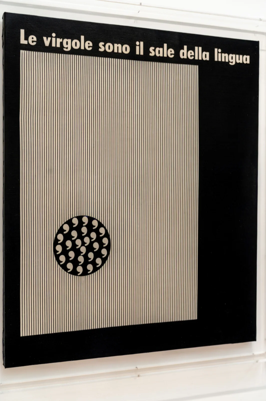 A canvas showing a field of close vertical lines beneath a line of newspaper-style type reading Le virgole sono il sale della lingua, with a circle of commas suspended below