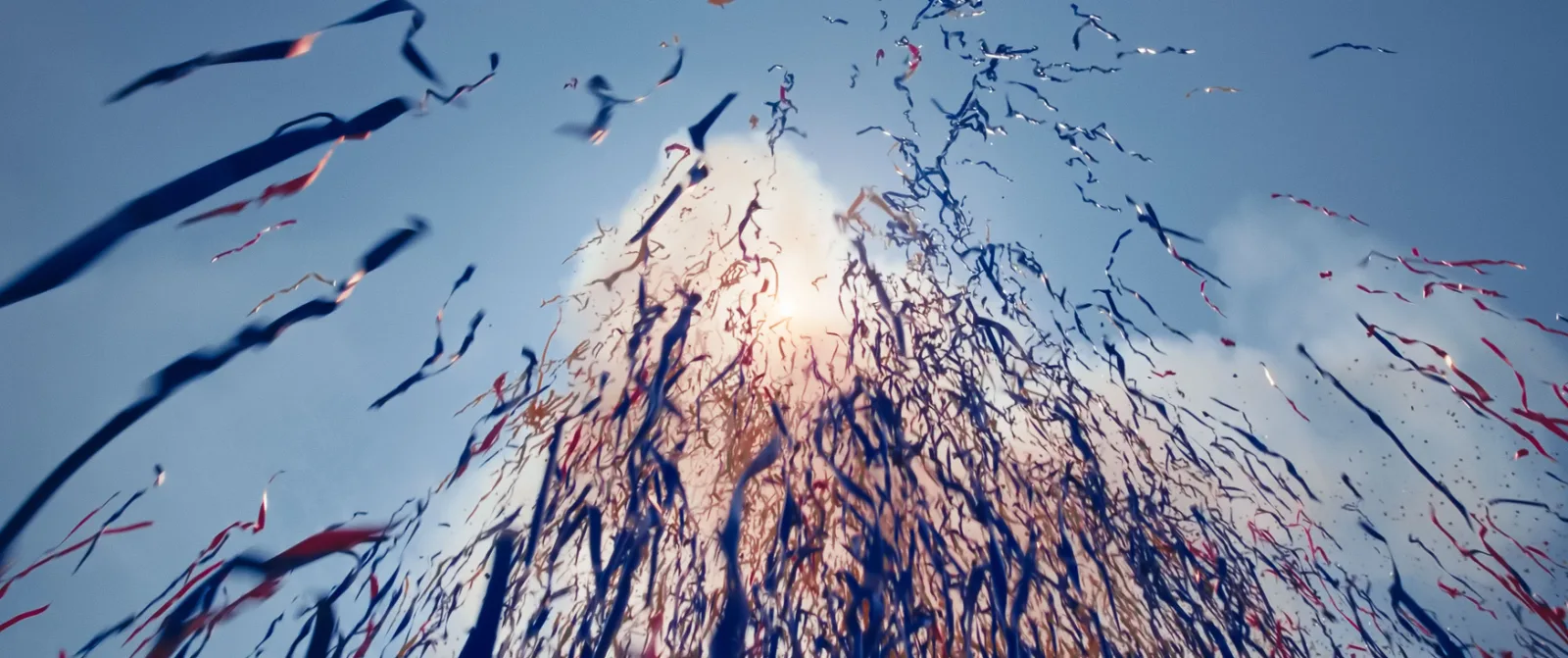 Streamers exploding against a blue sky with the sun behind them, resembling a volcanic eruption, still from She Flickered In and Out of History