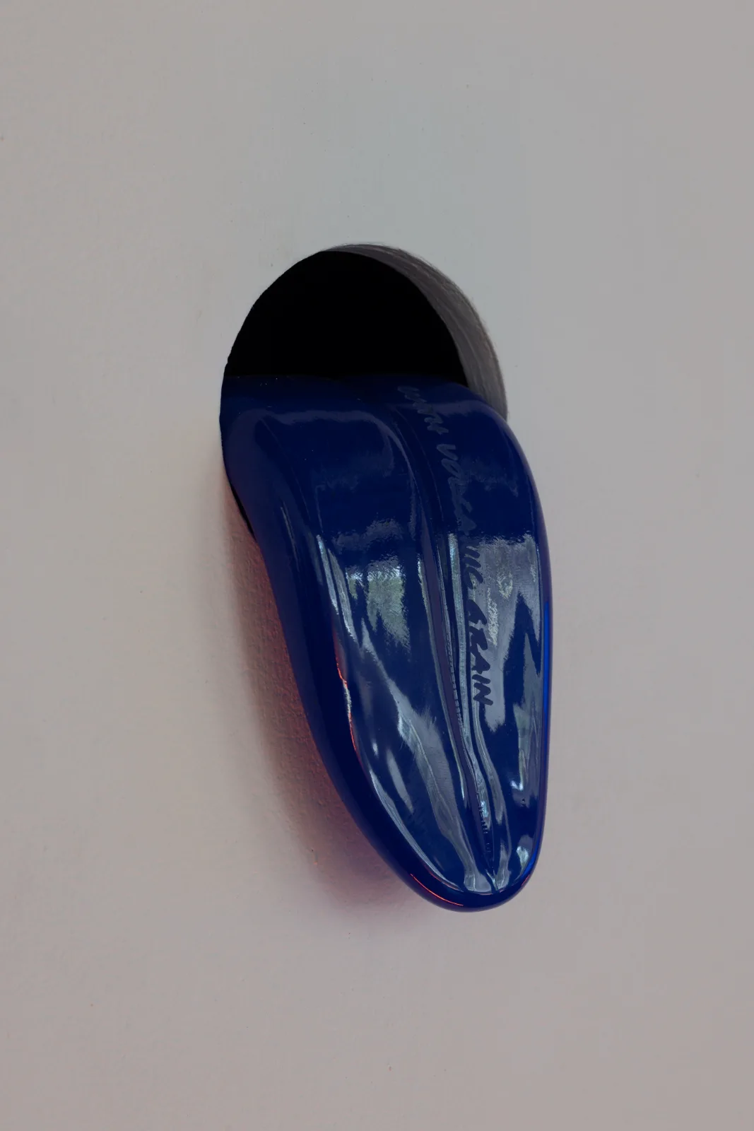 A blue glass tongue emerging from a circular opening in the gallery wall, inscribed with a fragment of the film's poem