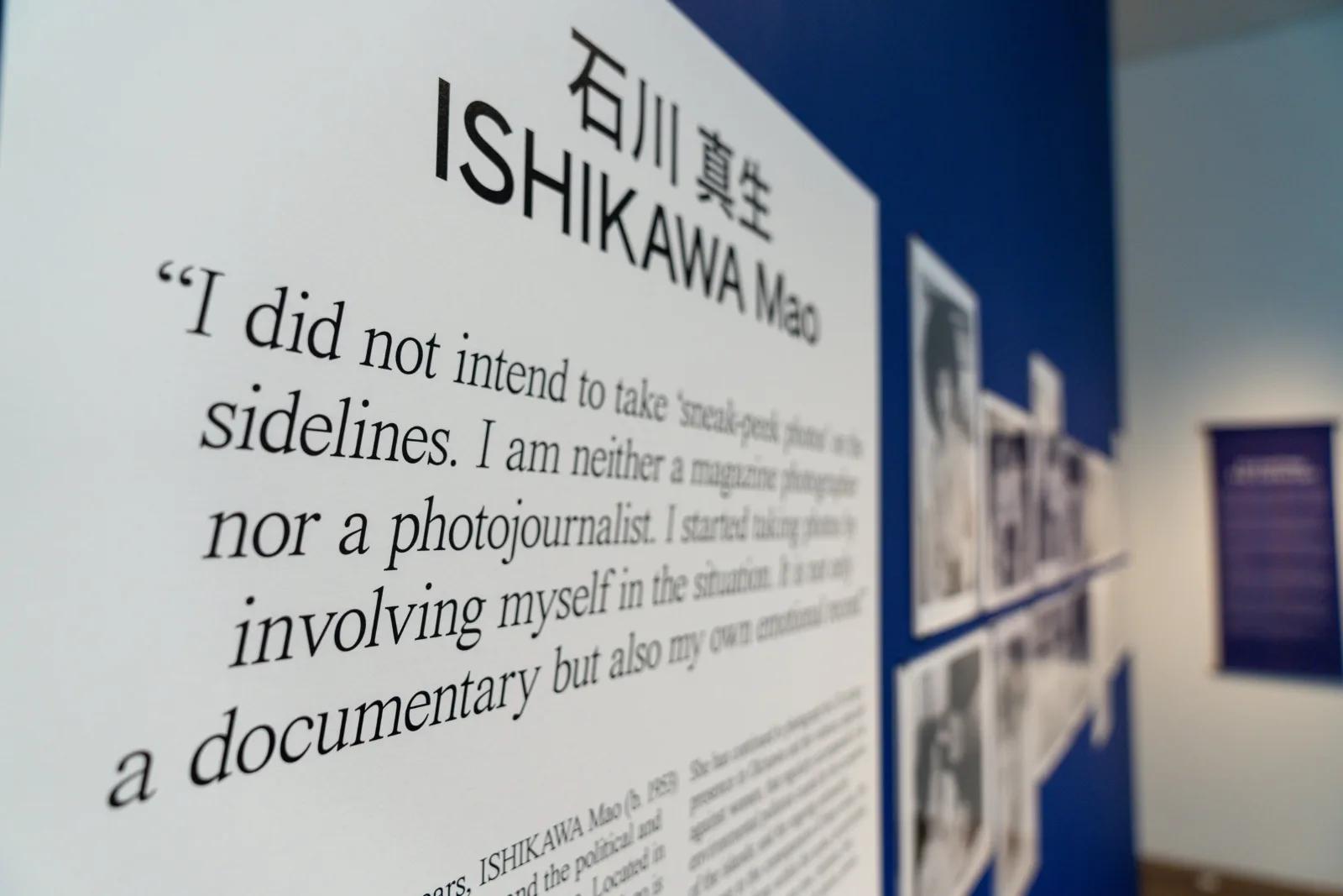 Close-up of a wall text with the name Ishikawa Mao in Japanese and English and a large quotation, on a deep blue wall