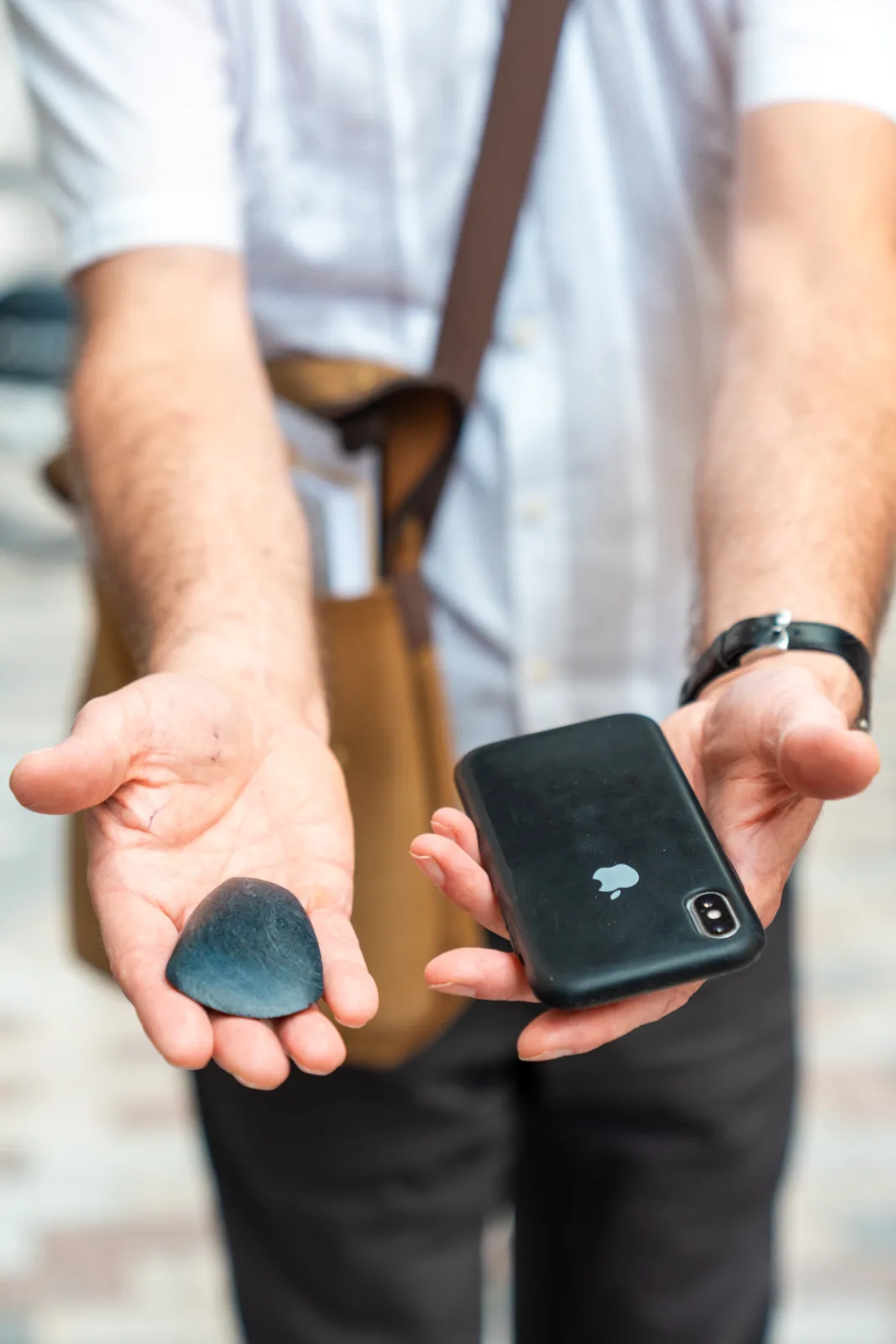 Two open hands, one holding an ancient carved object, the other a mobile phone