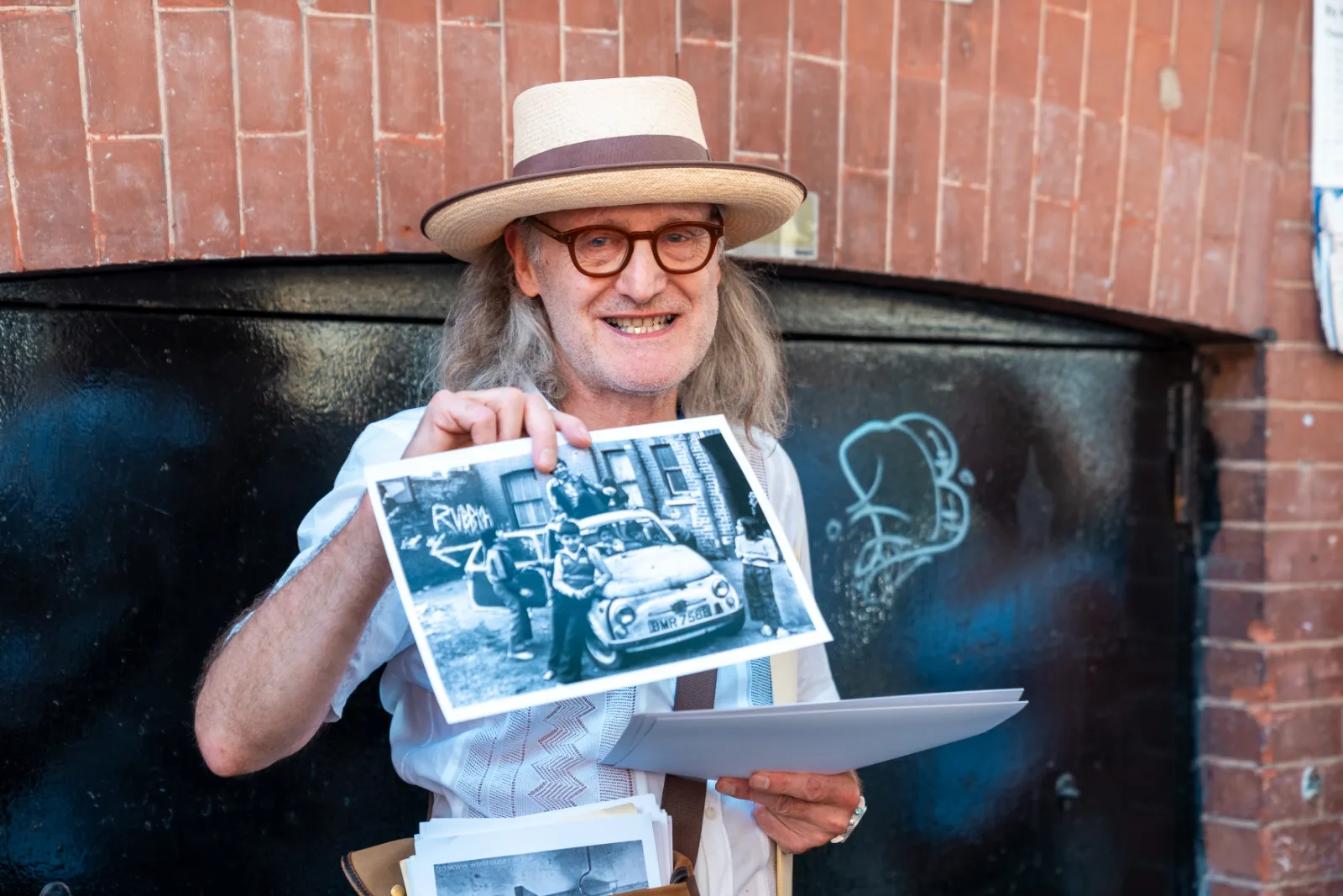 The Gentle Author holding a historic print up against a graffitied shutter on the Whitechapel Road