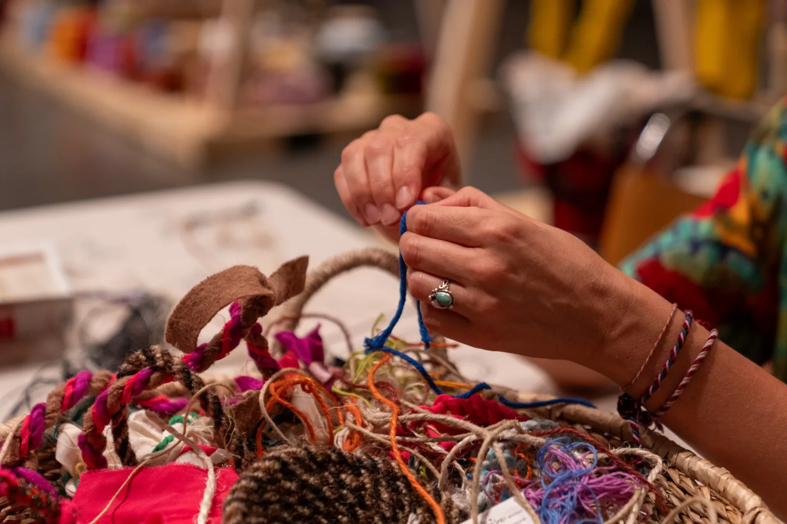 Hands working above the growing installation of coloured cord and rope