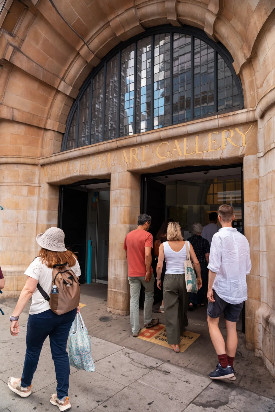 Visitors entering the Whitechapel Gallery through its arched stone entrance