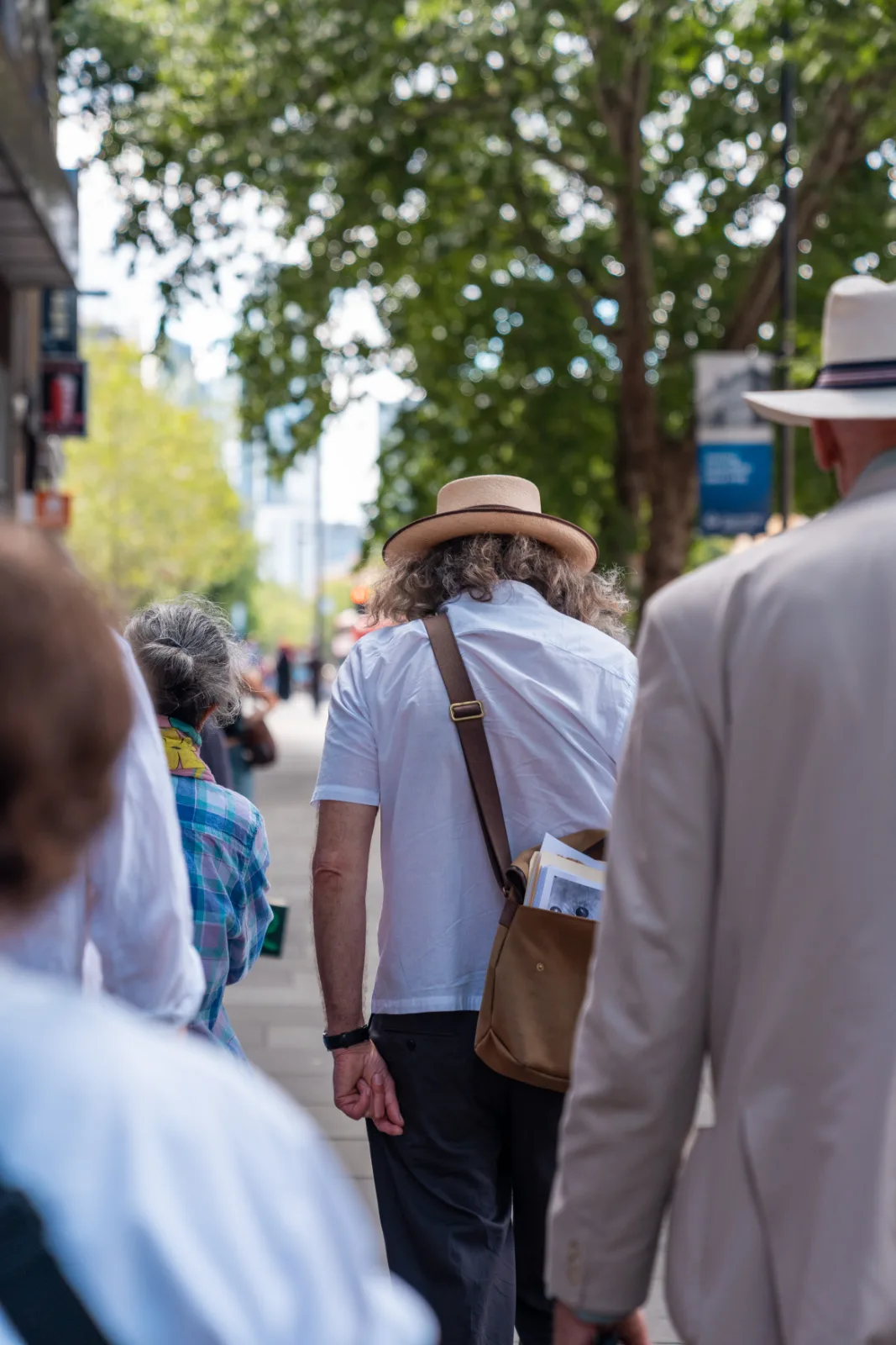 The Gentle Author walking ahead of the group along the Whitechapel Road, a canvas satchel of prints at his side