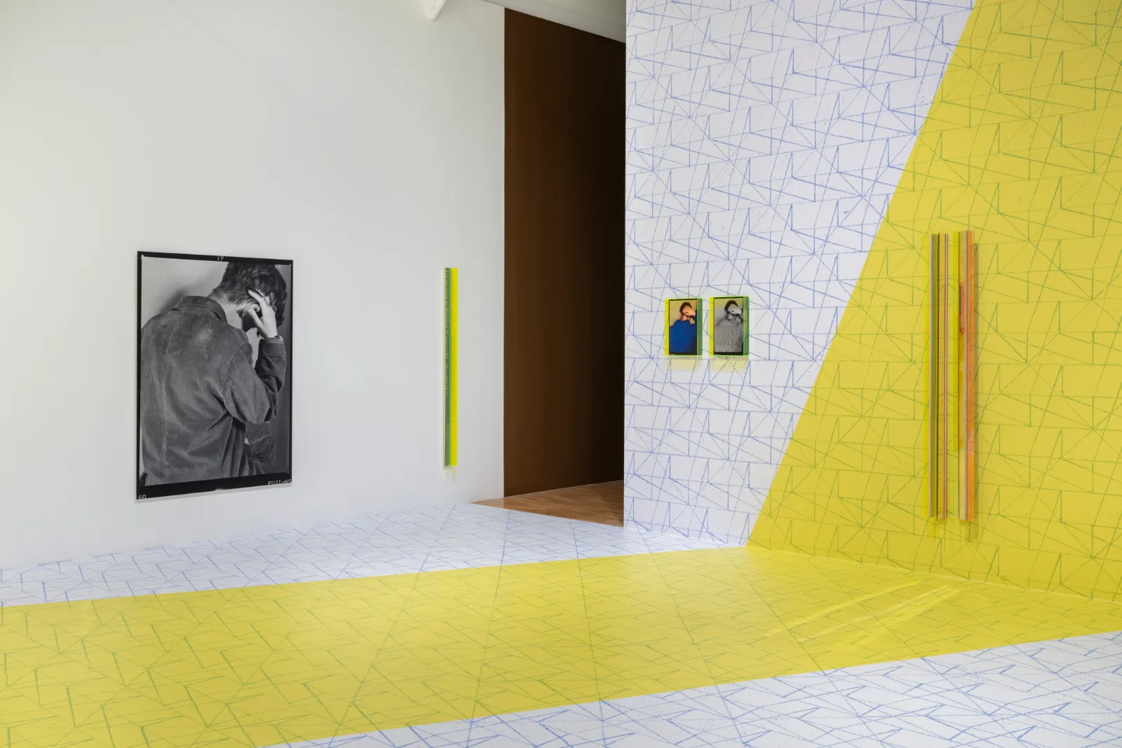 Installation view of East of the Aldgate Pump, a gallery with a blue and yellow geometric pattern running across walls and floor